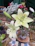Close-up of a sleek metal flower vase holding fresh white lilies on a wooden table.