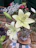 Close-up of a sleek metal flower vase holding fresh white lilies on a wooden table.