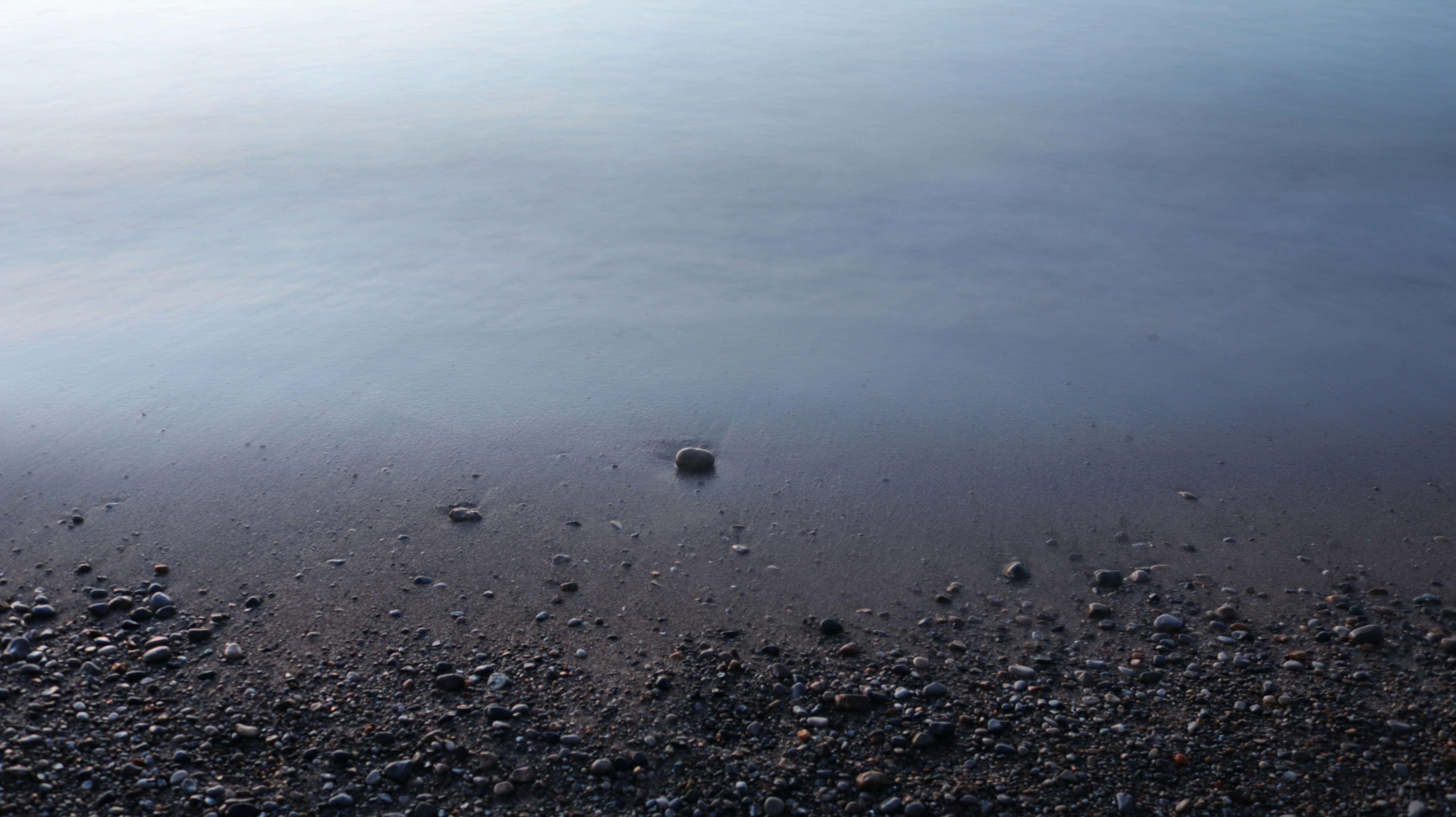 a rocky beach with a body of water in the background