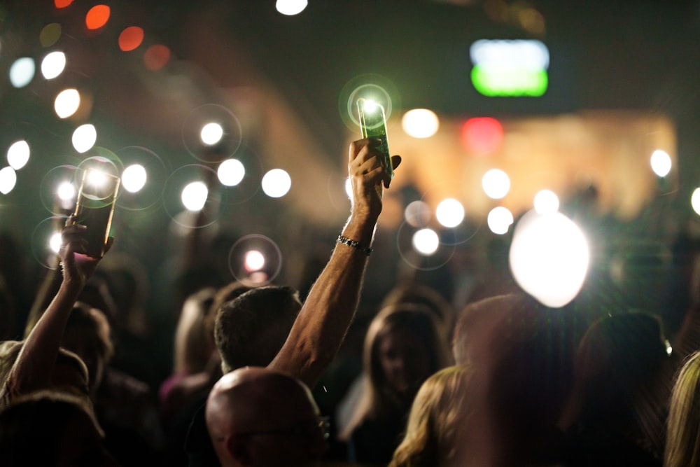a crowd of people holding up a green light