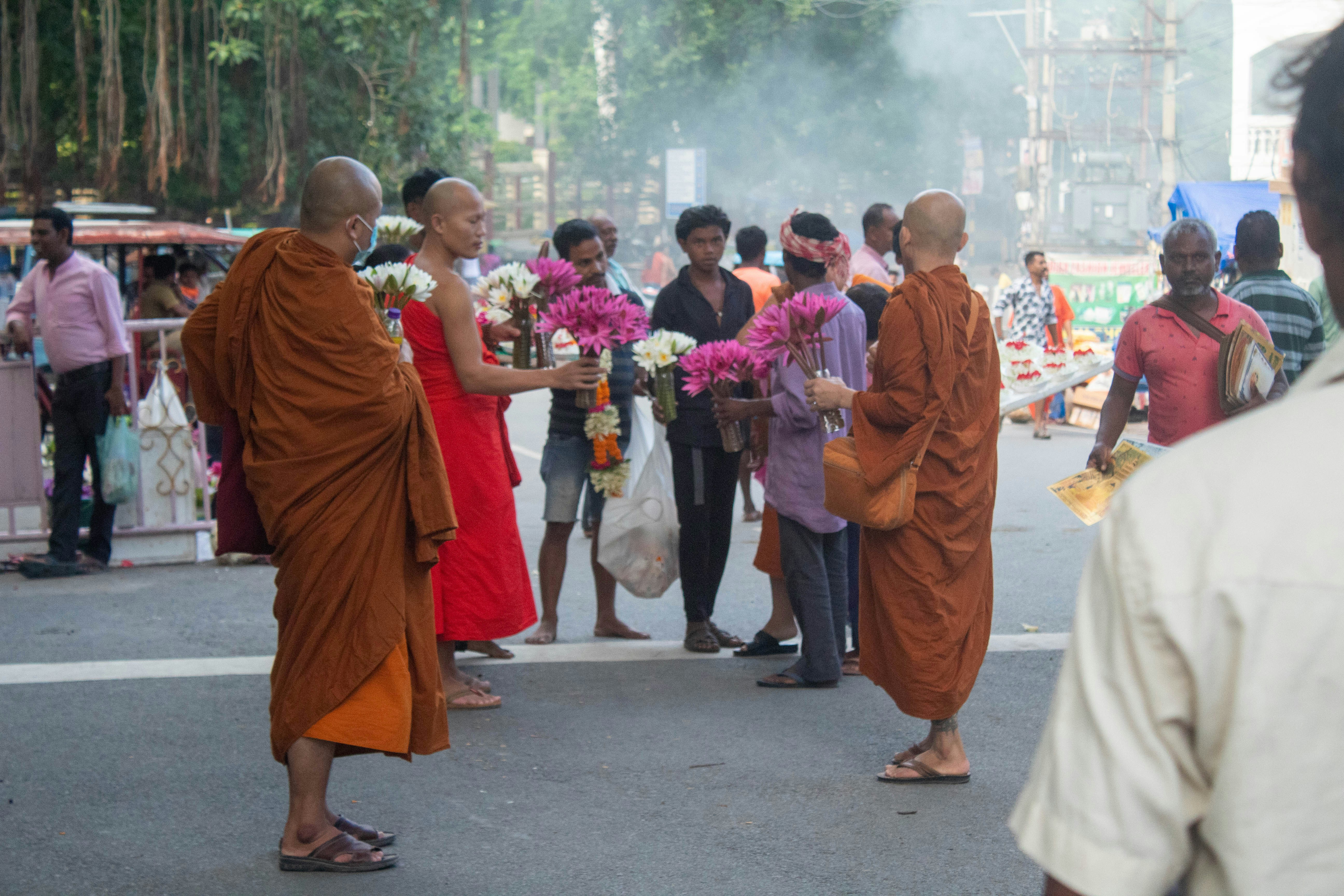A group of international tourists, some in traditional Buddhist attire, smiling as they embark a train or visit a stupa in Bodhgaya.
