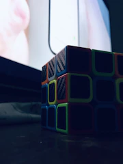 A sleek neon-lit puzzle cube rotating slowly against a black and purple backdrop