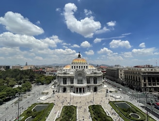 a large building with a gold domed roof surrounded by a parking lot with Palacio de Bellas Artes in the background