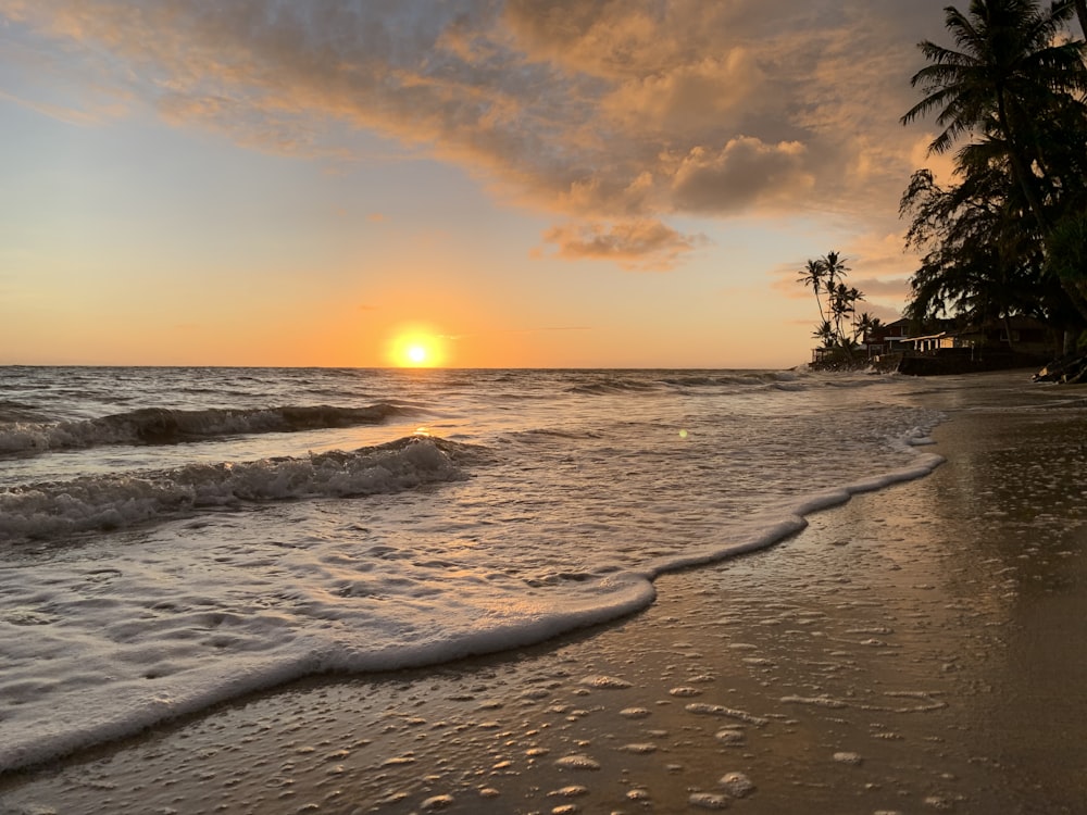 a beach with waves and a sunset