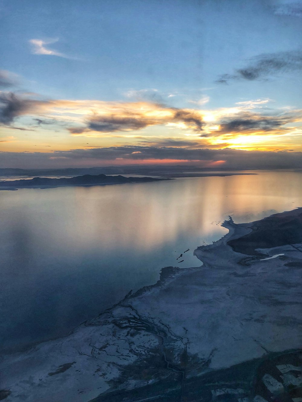 a snowy landscape with a body of water and a sunset