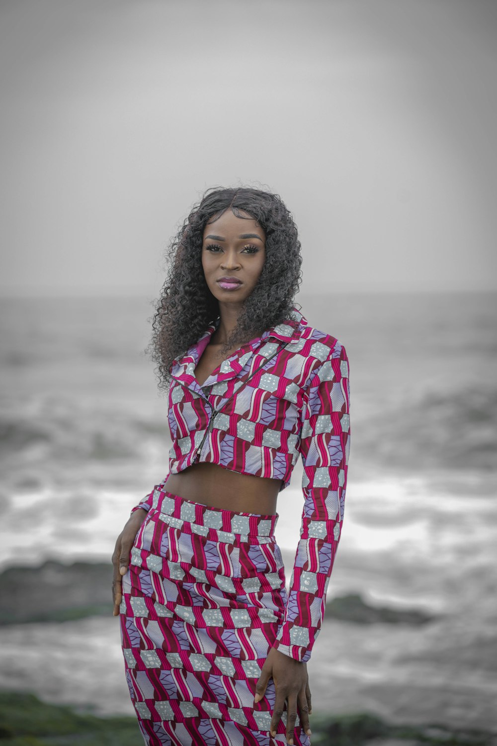 a person in a dress standing on a rocky beach