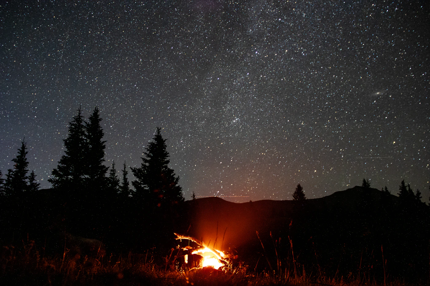 Fogata encendida de noche bajo un cielo lleno de estrellas