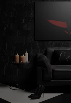 A moody, refined living room featuring warm black and taupe tones with minimalist furniture and architectural details.