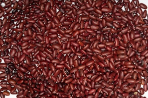 A large pile of reddish-brown kidney beans closely packed together, with their shiny surfaces catching the light.