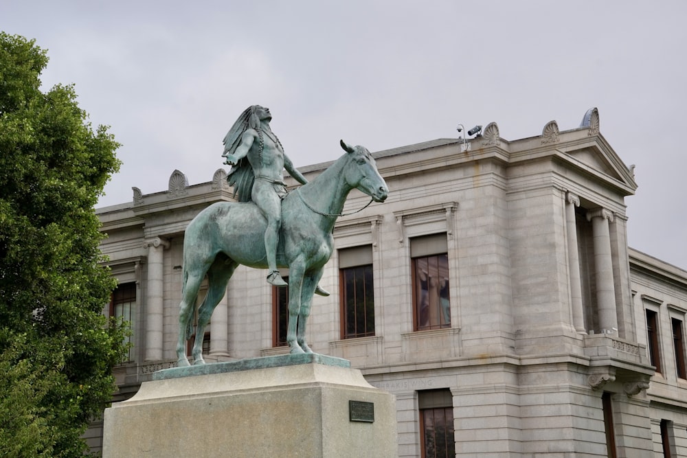 Una estatua de una persona montando a caballo frente a un edificio