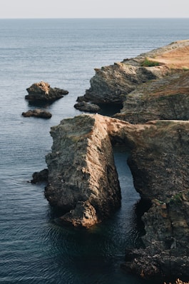 a rocky cliff with a body of water below