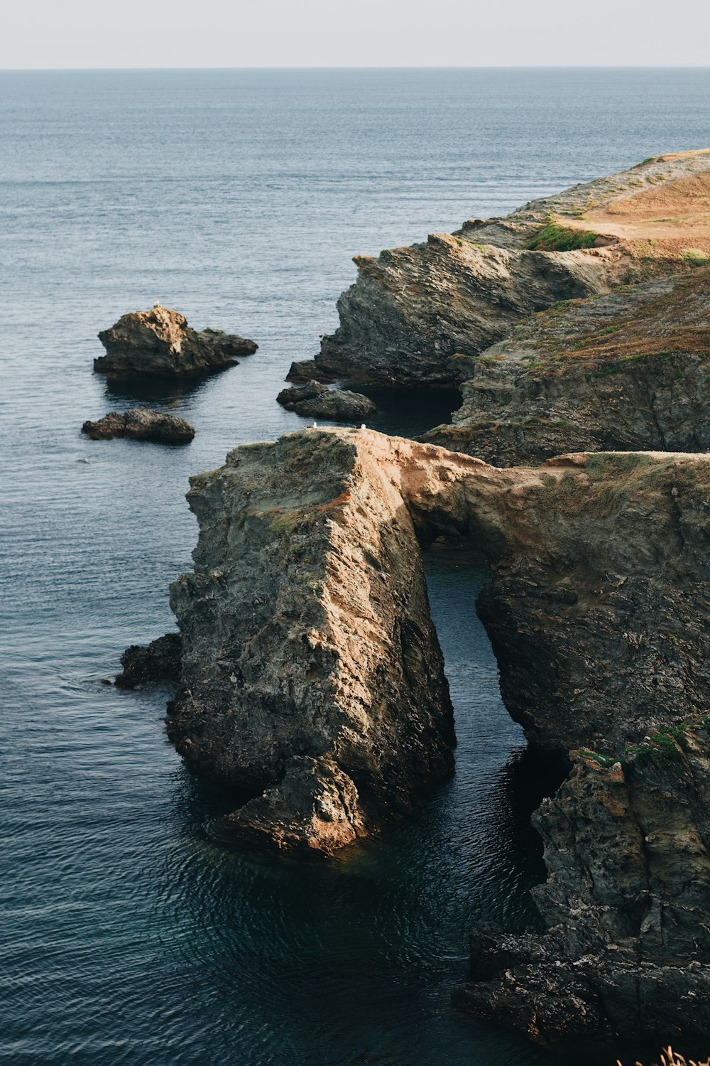 a rocky cliff with a body of water below