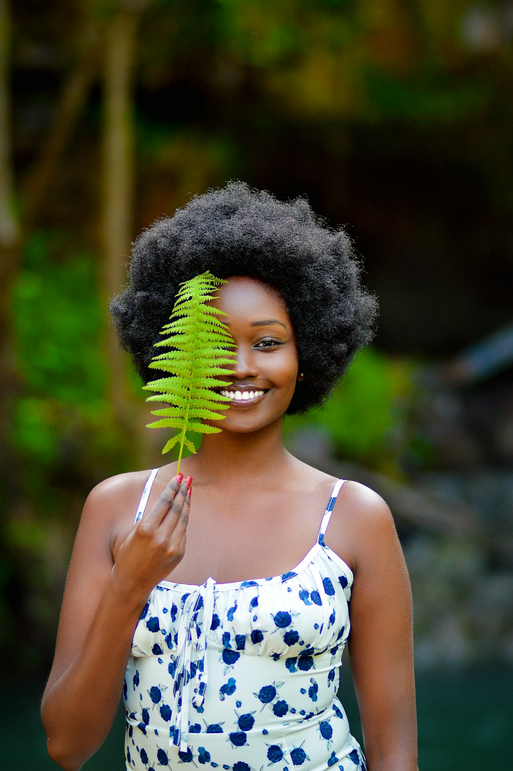 a person with a green face and a blue dress holding a green plant