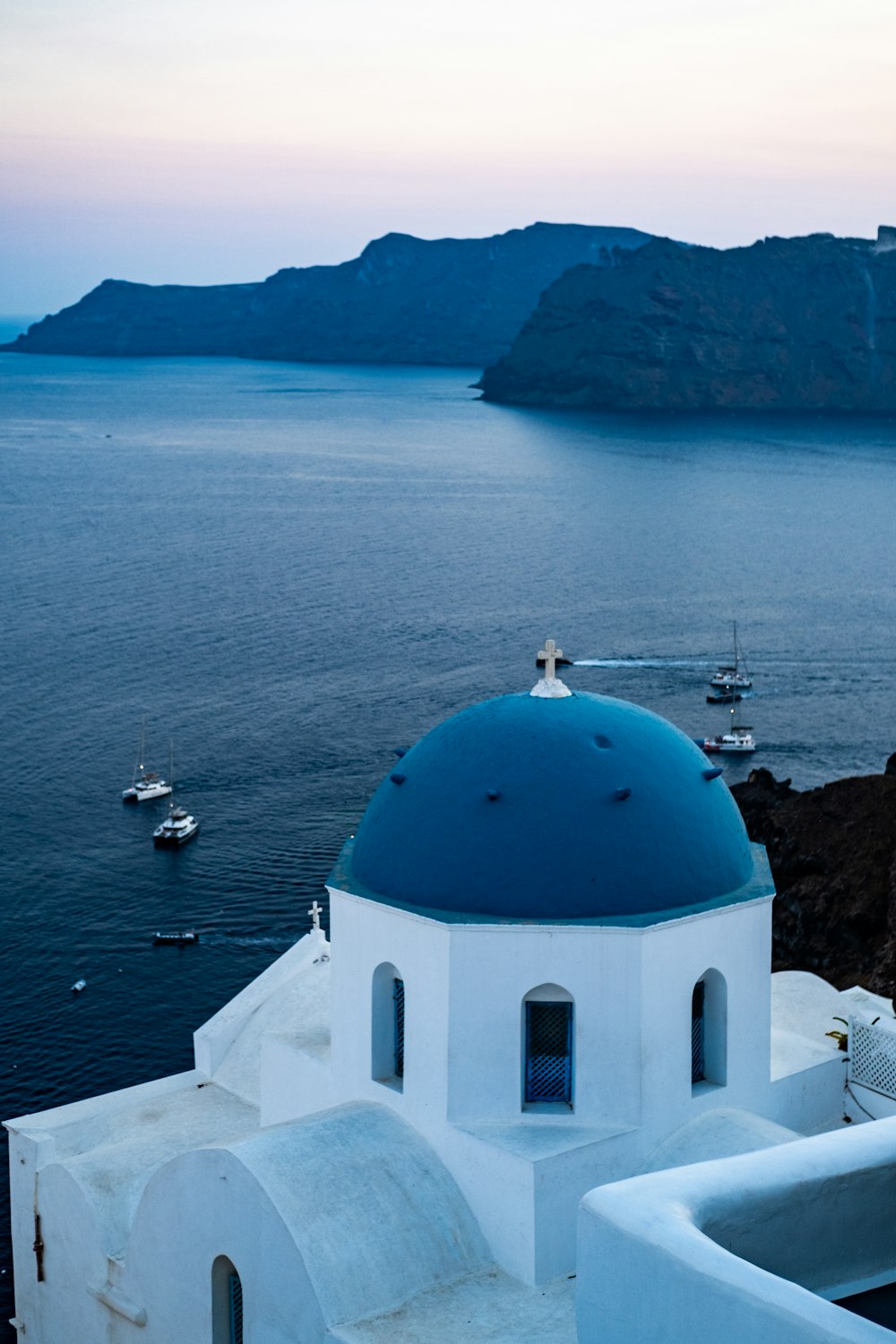 a white building with a blue dome and boats in the water