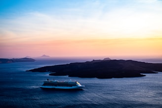 A serene cruise ship gliding over turquoise blue waters at sunset.