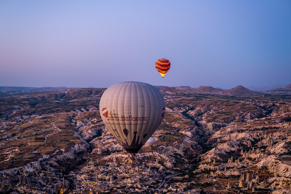 a couple of hot air balloons in the sky over a canyon