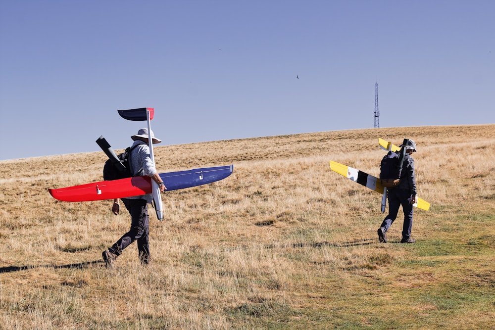 a couple of men carrying a small airplane on a field