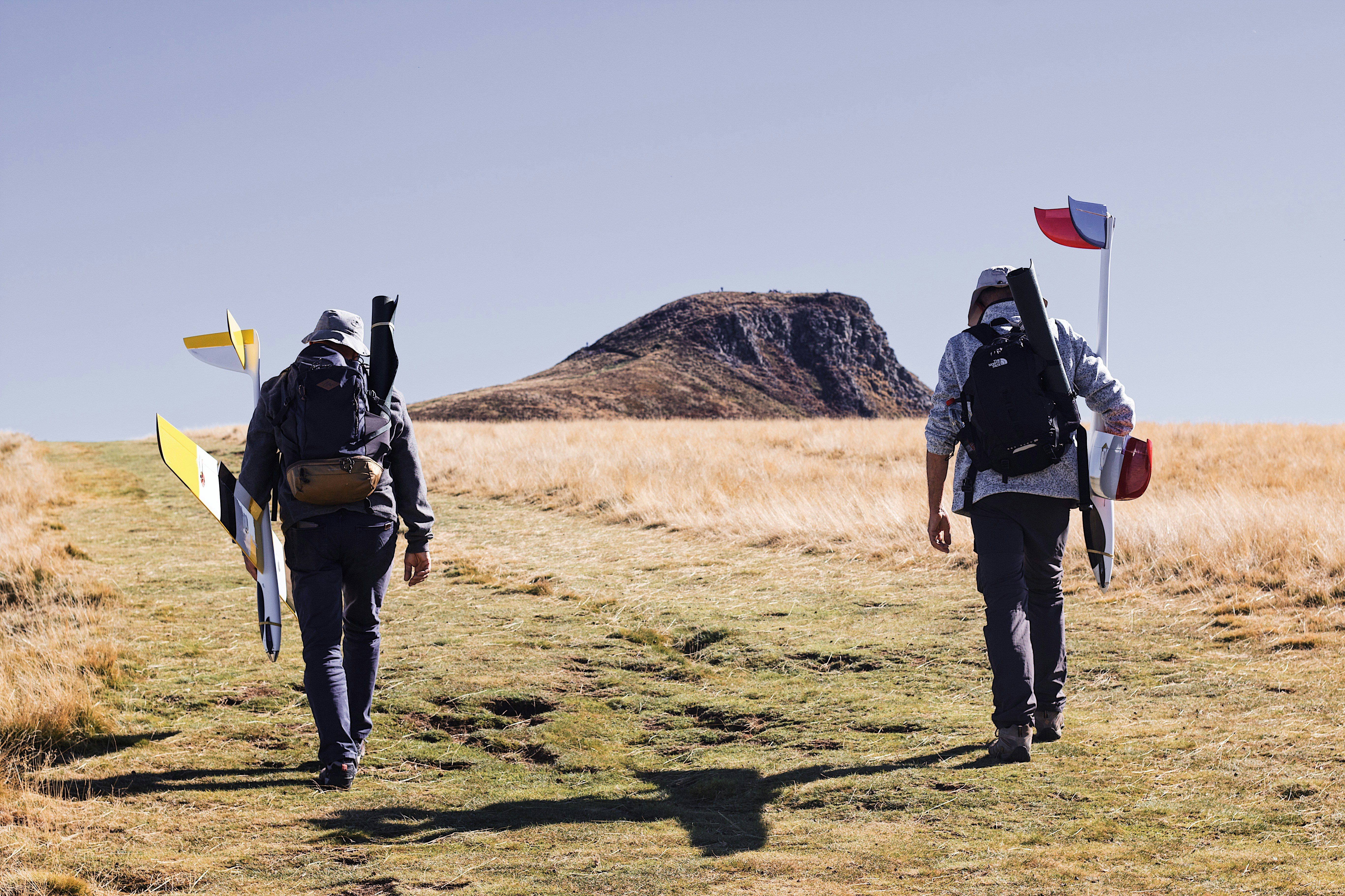 a couple of people walking with surfboards on a field