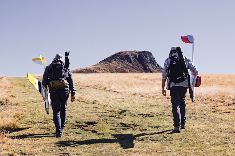 a couple of people walking with surfboards on a field