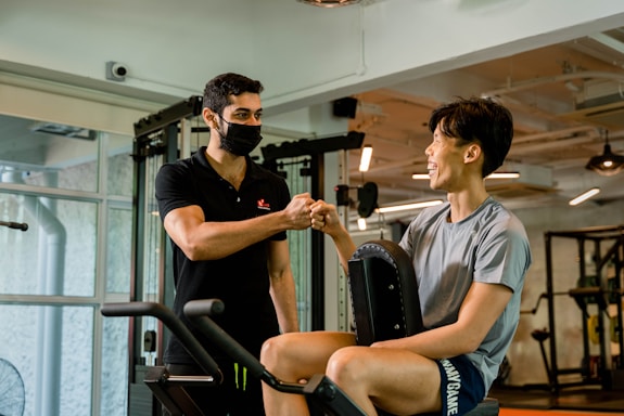 A friendly trainer shaking hands with a client in a bright gym setting