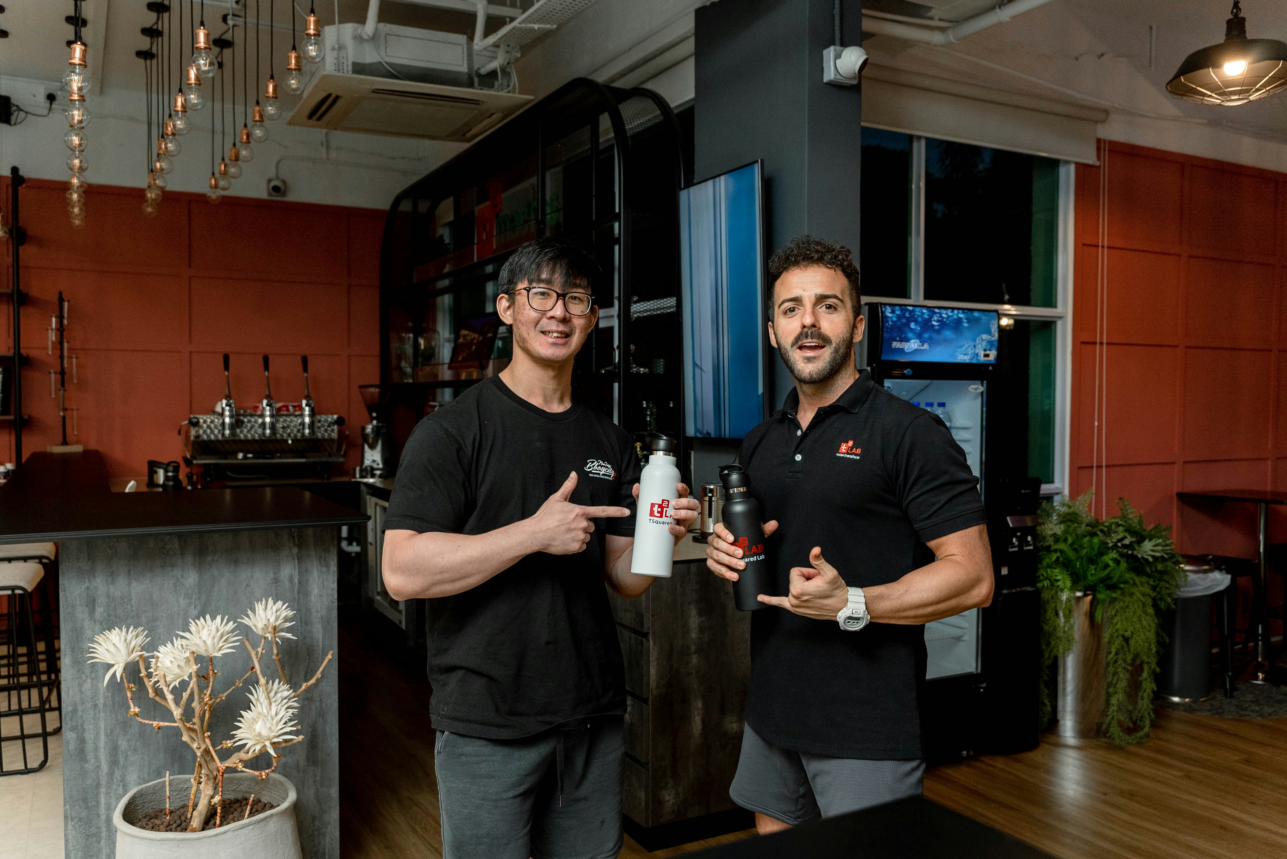 Two men holding a white bottle in a modern gym.