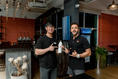 A friendly agent delivering Airtis water gallons to a modern cafe with a welcoming atmosphere.