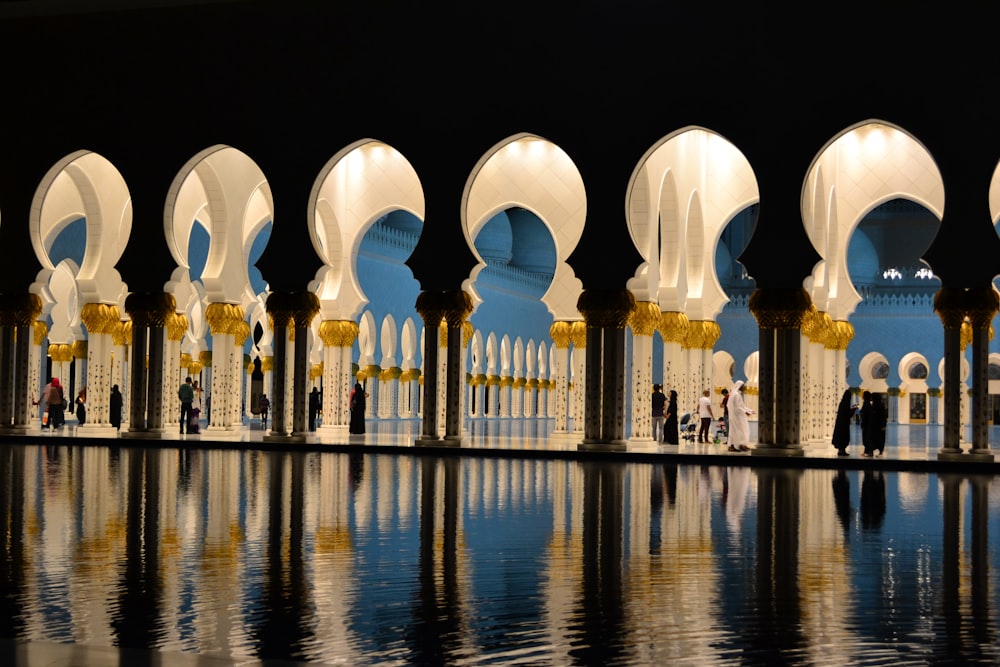a large building with arches and columns with Sheikh Zayed Mosque in the background