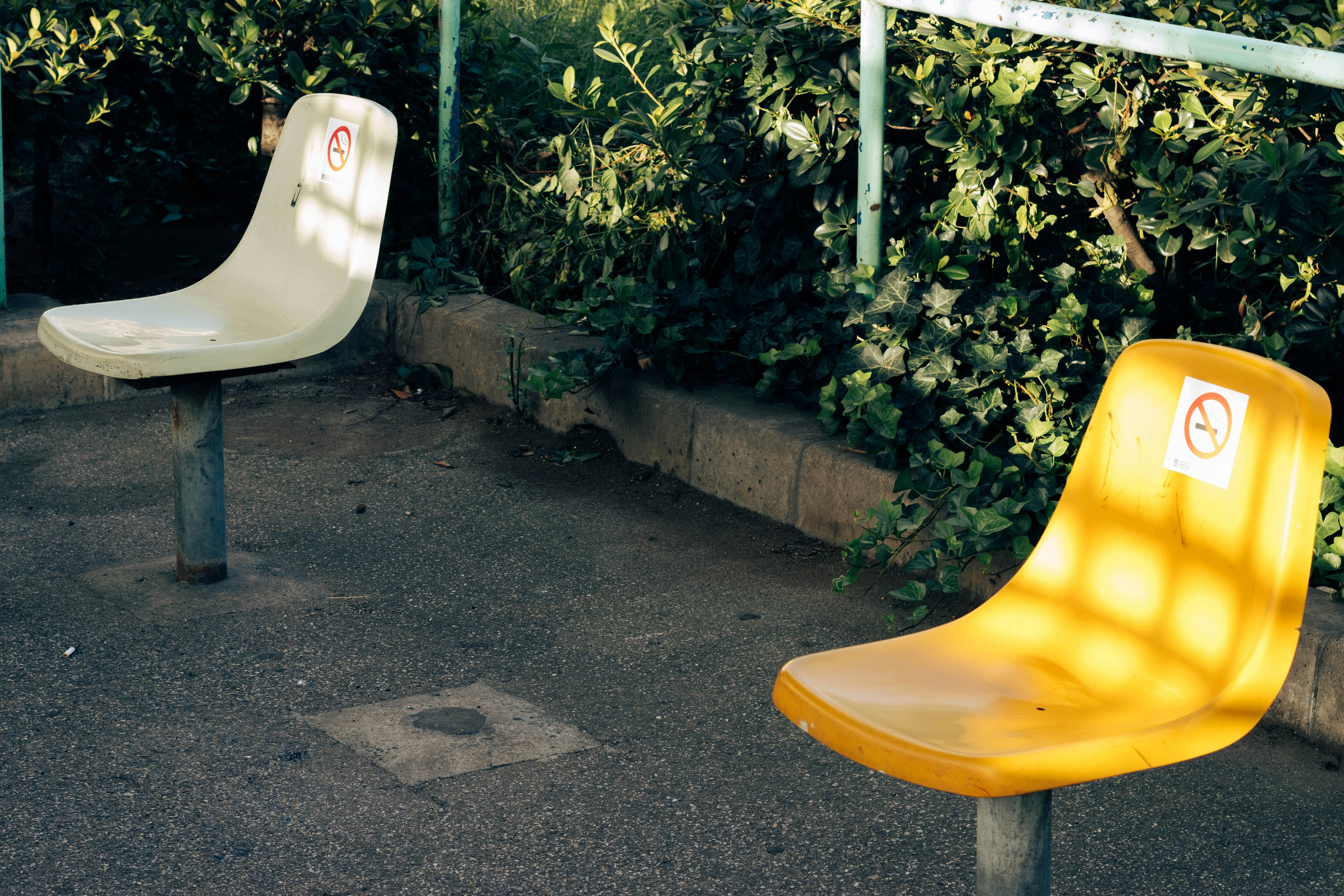 a yellow plastic chair next to a white and green plastic chair