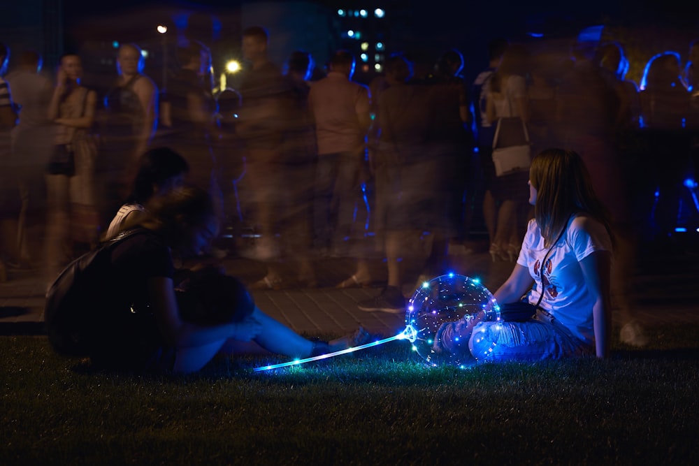 a group of people sitting on the ground with a light in the back