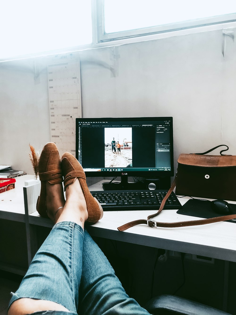 a person's feet on a desk with a computer and a guitar