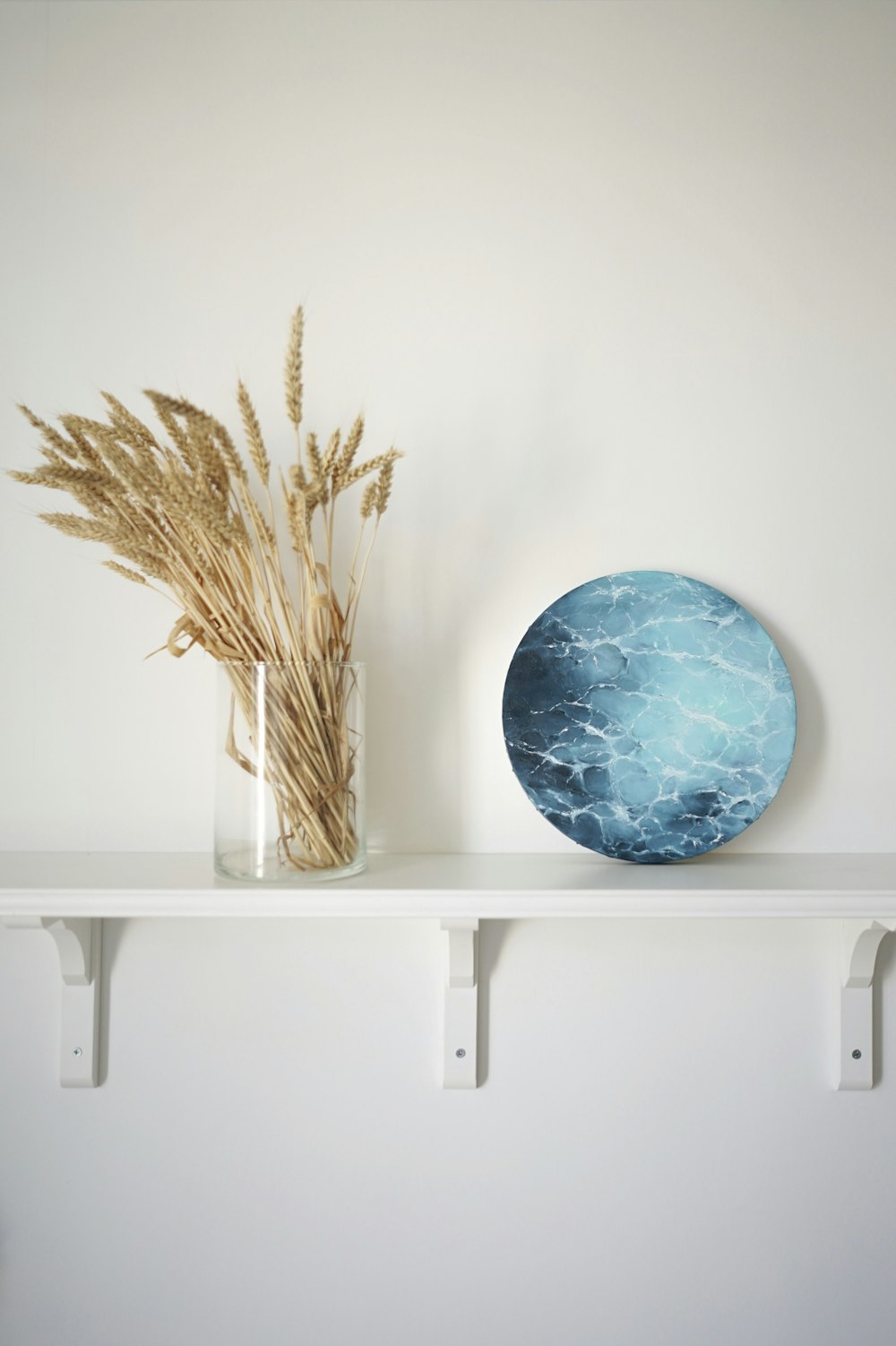 a blue vase and a vase on a white shelf