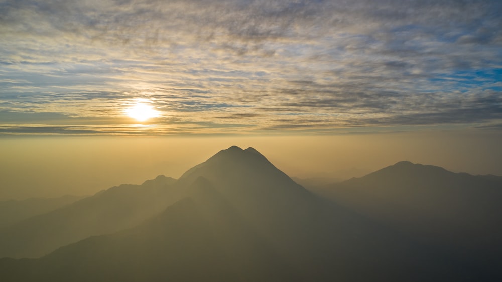 a mountain with the sun in the background