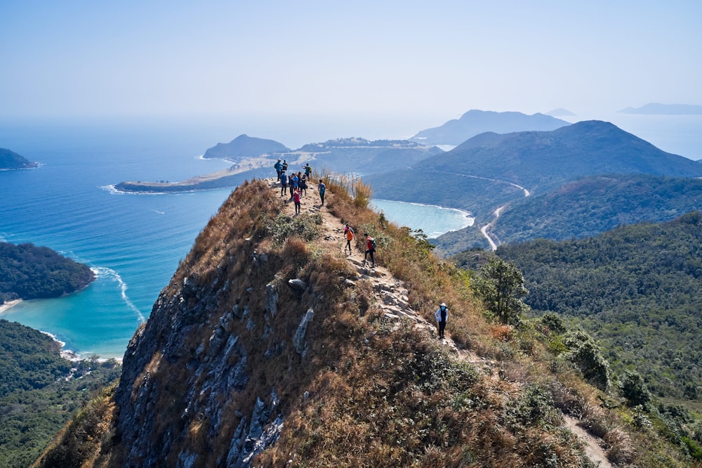 a group of people walking on a cliff above a body of water