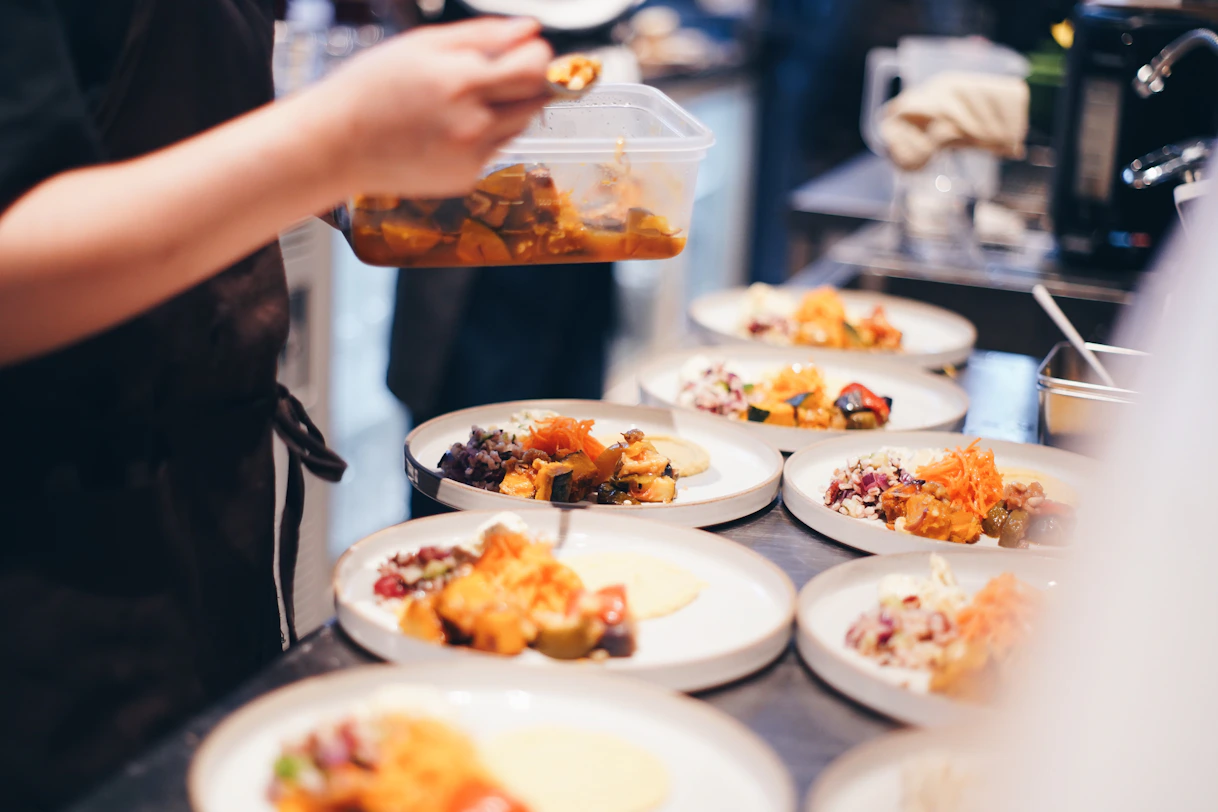 A chef plating a colorful, artfully arranged seafood dish in a bustling kitchen.
