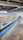 A supermarket aisle contains a long refrigerated display filled with various packaged products. Bright lighting illuminates the area, highlighting items such as meats and dairy. The floor is polished concrete, and a shopping cart is visible in the distance.