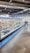 A supermarket aisle contains a long refrigerated display filled with various packaged products. Bright lighting illuminates the area, highlighting items such as meats and dairy. The floor is polished concrete, and a shopping cart is visible in the distance.