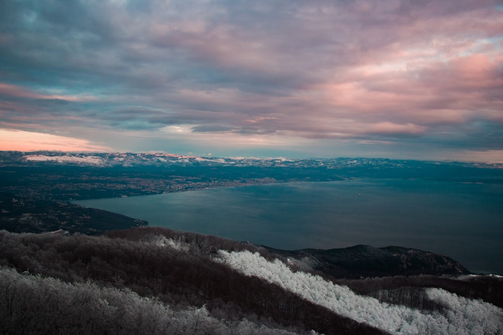 a snowy landscape with a body of water in the distance