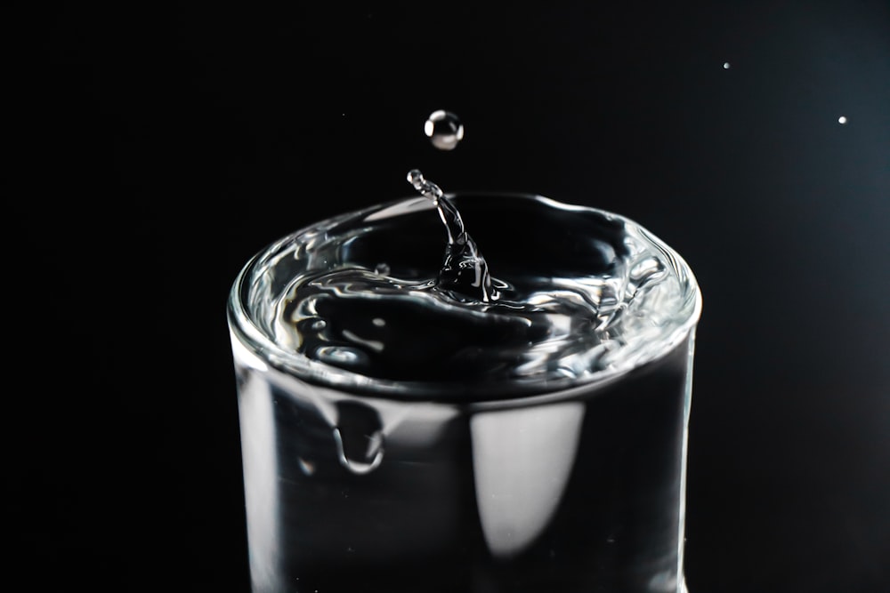 a glass of water with a drop of water falling into it