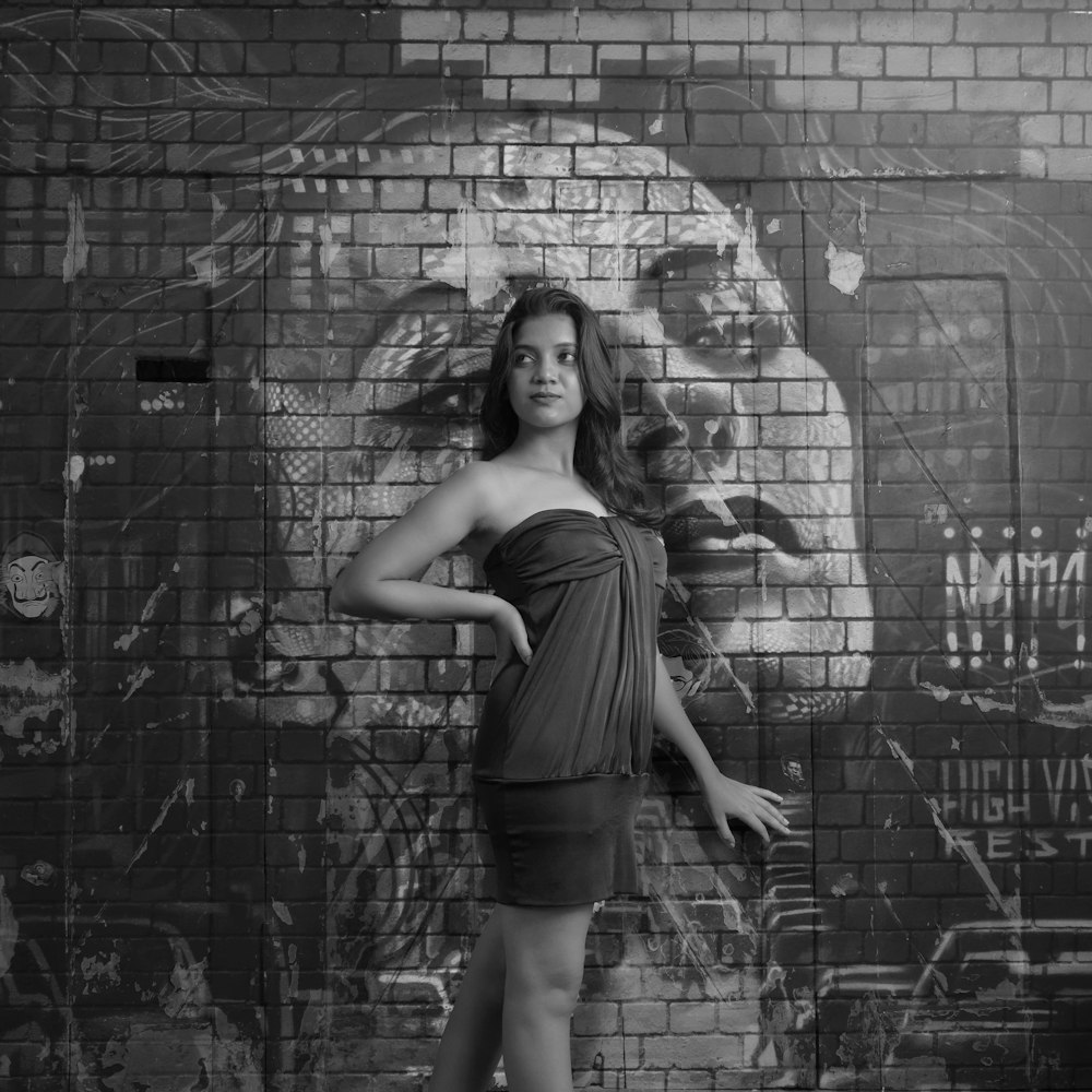 a woman posing in front of a brick wall