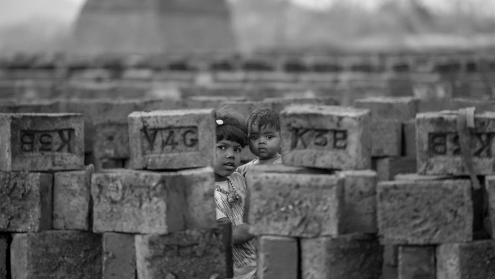 a couple of children standing on a stone wall