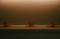 A set of three copper water bottles arranged on a soft cream fabric, reflecting antique gold hues.