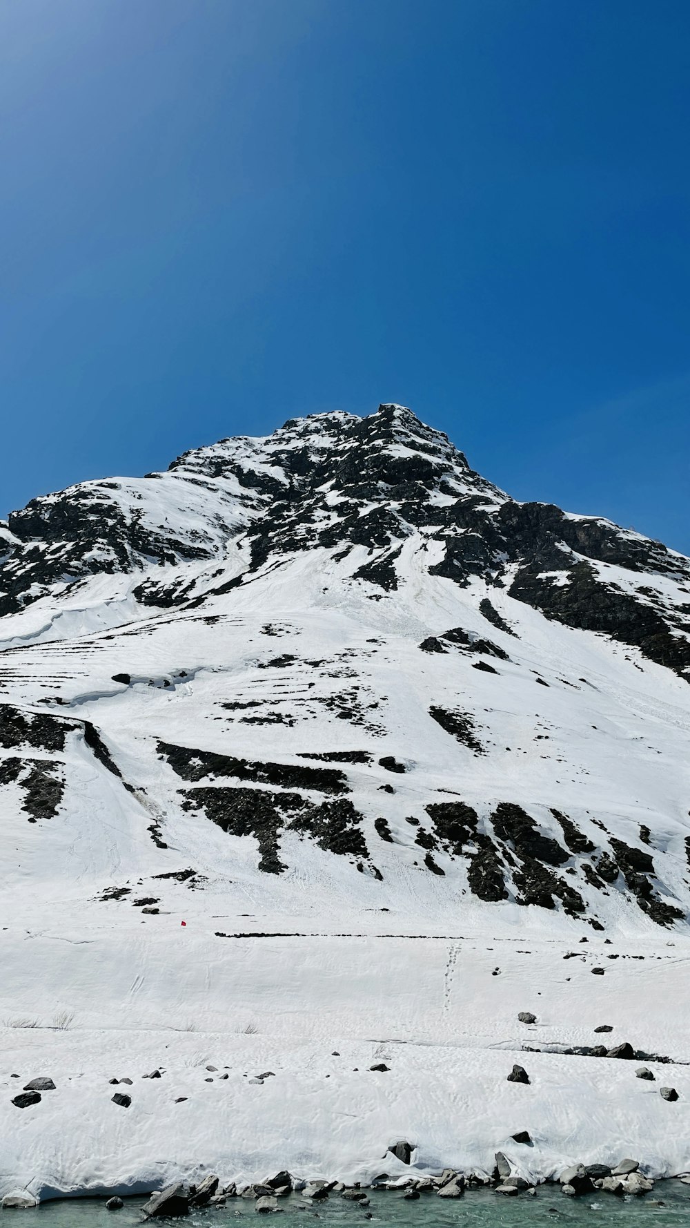 a snowy mountain with a body of water below