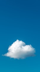 A fluffy white cloud floats against a clear, vivid blue sky. The cloud appears soft and billowy, contrasting beautifully with the deep azure backdrop.