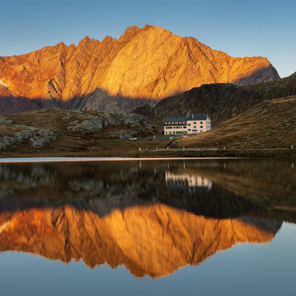 a house on a hill by a lake with a mountain in the background