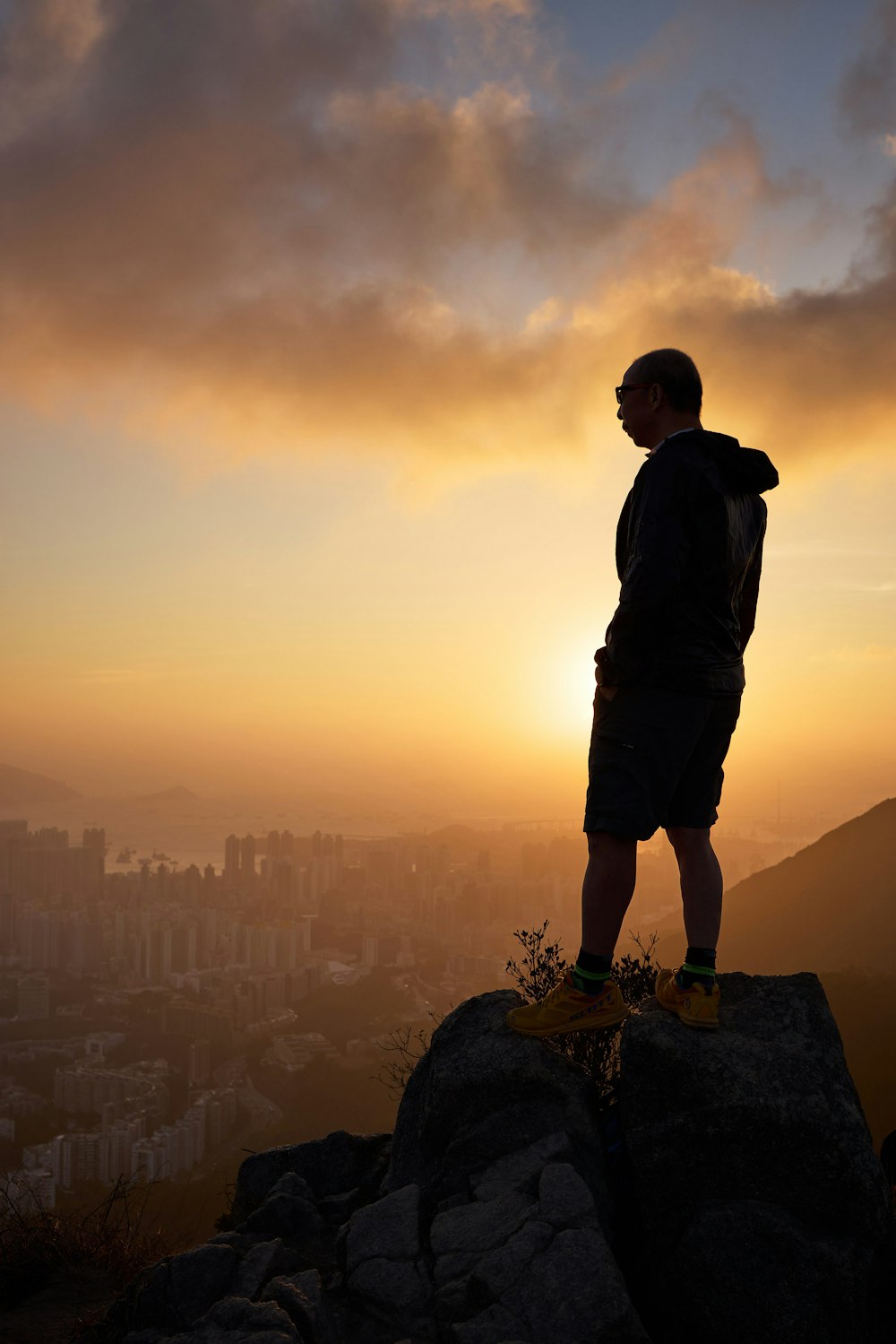 a man standing on a rock overlooking a city