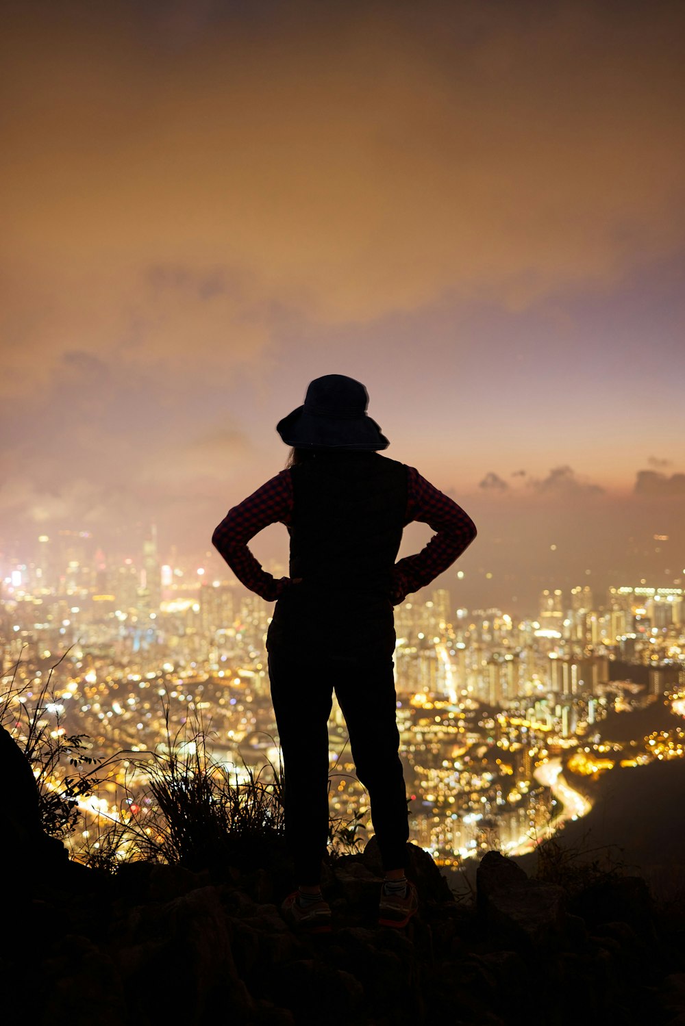 a person standing on a ledge overlooking a city at night