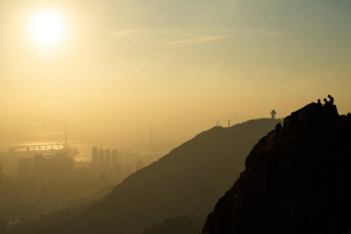 Hikers on the crags of Lion Rock at sunrise, with the city in the haze below