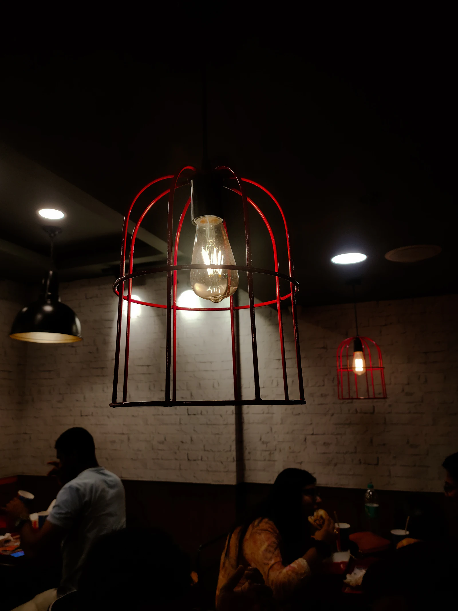 Guests dining beneath a glowing red pendant light