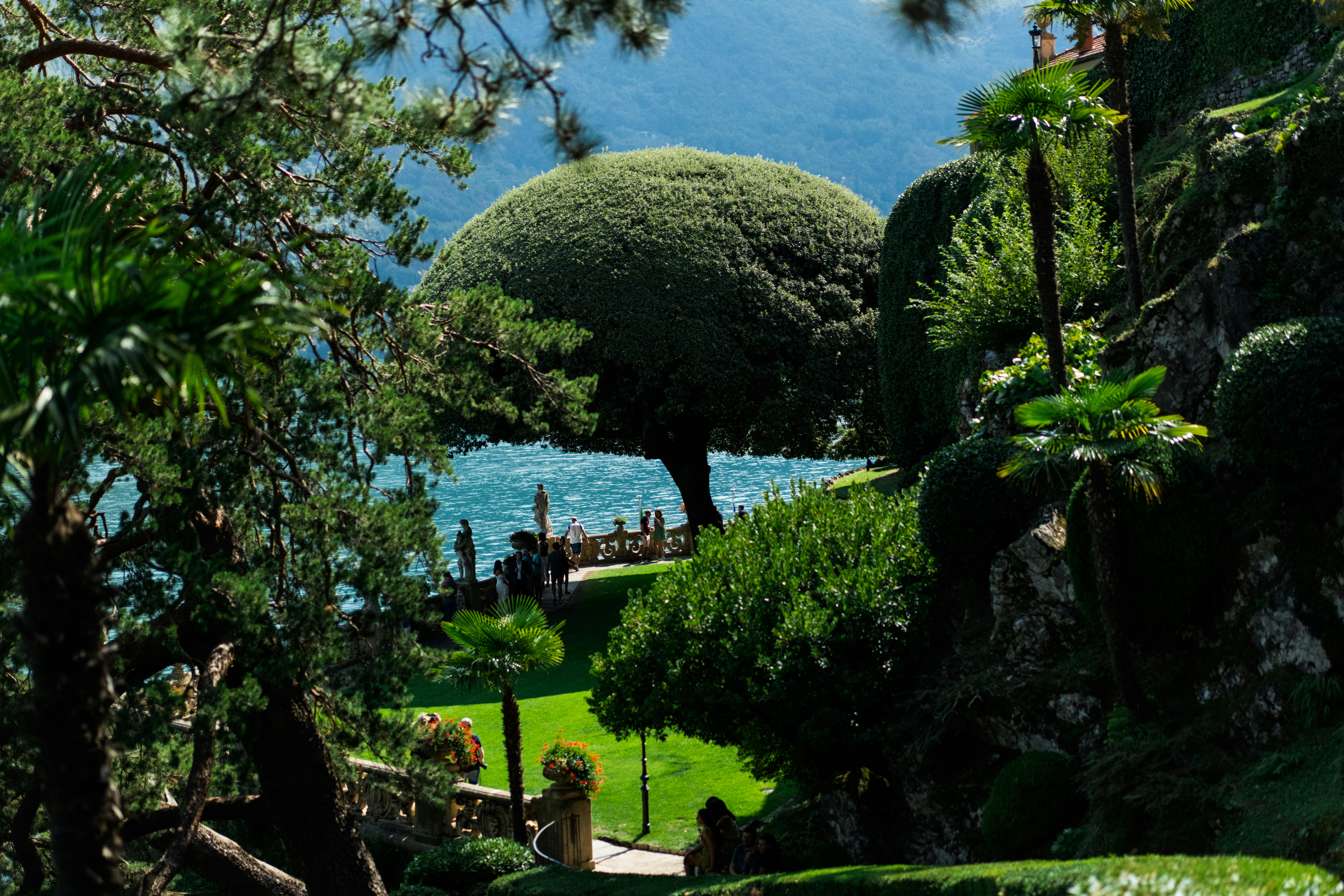 a large green landscape with a body of water in the background, Villa del Balbianello - Lake Como, Italy.