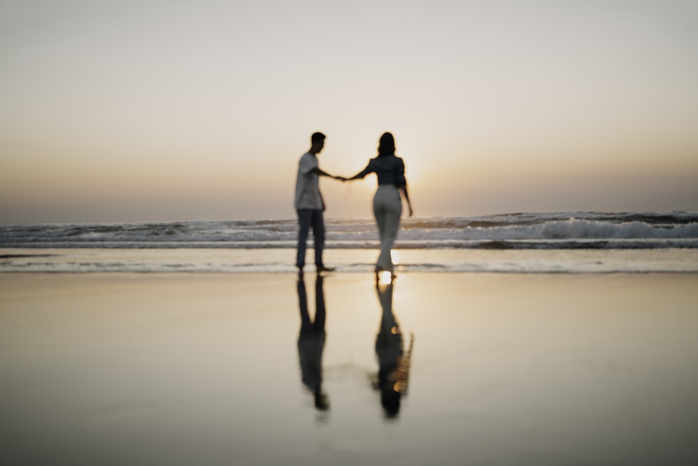 a man and woman holding hands on a beach